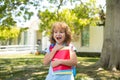 Back to school. Child with rucksacks standing in the park near school. Pupils with books and backpacks outdoors.