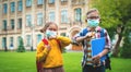 Back to school. Children with face mask going back to school after covid-19 lockdown. Boy and girl with backpacks