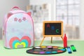 Back to school. Colorful school equipment, a bright school backpack and a blackboard with ABC letters on green table over an Royalty Free Stock Photo