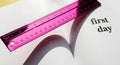Back to school composition: A pink ruler resting on an open book that says \'first day Royalty Free Stock Photo