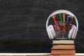 Back to school. Composition from a stack of books pencils glasses headphones on a black chalk board background. Royalty Free Stock Photo