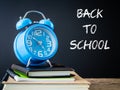 Alarm clock on stacks of books on wooden table and black background. Royalty Free Stock Photo