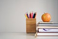 Back to school concept. Apple on books, notebook, colour pencils in stand, light gray background. Royalty Free Stock Photo