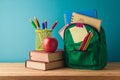 Back to school concept with backpack, pencils, books and apple on wooden table over blue background Royalty Free Stock Photo