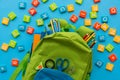 Back to school concept. Backpack with school supplies and alphabets and numbers blocks on blue background. Top view. Copy space Royalty Free Stock Photo