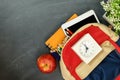 Back to school concept. Backpack with school supplies, clock, tablet and apple against chalk board. Top view. Copy space Royalty Free Stock Photo