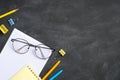 Back to school concept. Blank paper notebook, glasses and school supplies on black board background. Flat lay, top view, copy Royalty Free Stock Photo