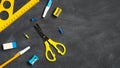 Back to school concept. Blue and yellow school supplies on black board background. Flat lay, top view, overhead Royalty Free Stock Photo