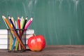 Back to school concept. Close-up photo of colorful crayons red apple and textbooks isolated on green chalkboard Royalty Free Stock Photo