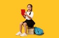 Cute School Girl Reading Book Sitting On Books, Yellow Background Royalty Free Stock Photo