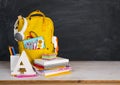 Back to school concept. Educational supplies on table before blackboard