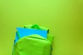 Back to school concept. Green backpack with school supplies on green background. Top view.
