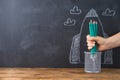 Back to school concept with hand holding pencils over chalkboard rocket sketch background Royalty Free Stock Photo