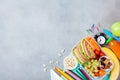 Back to school concept. Healthy lunch box and colorful stationery on gray table top view.