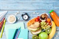 Back to school concept. Healthy lunch box and colorful stationery on turquoise wooden table top view.