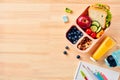 Back to school concept. Lunch box with healthy meal, paper notebook, colorful school stationery on wooden desk table