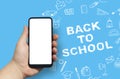 Back to School concept. Man Hand holding the black Mockup smartphone with beautiful nails on the background with stationery icons