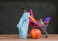 Back to school concept with pencils, crayons in shopping cart with apple with face mask Royalty Free Stock Photo