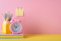 Back to school concept. Photo of school accessories on yellow desk stand for pens alarm clock stack of colorful notebooks and Royalty Free Stock Photo