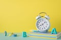 Back to school concept. Photo of school supplies on blue desktop alarm clock plastic alphabet letters stack of notebooks adhesive