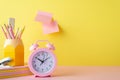 Back to school concept. Photo of school supplies pink alarm clock stack of notebooks pencils holder mini stapler and sticky note Royalty Free Stock Photo