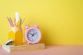 Back to school concept. Photo of school supplies on pink desk pen holder with pencils ruler alarm clock notebooks and stapler on Royalty Free Stock Photo