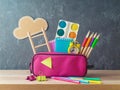 Back to school concept with pink pencil case on wooden table over blackboard background Royalty Free Stock Photo