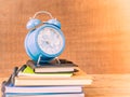 Retro style of alarm clock on stacks of books with wooden table background. Royalty Free Stock Photo