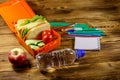 Back to school concept. School supplies, bottle of water, apple and lunch box with sandwiches and fresh vegetables