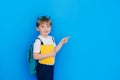 Back to school concept. Schoolboy boy with backpack and holding yellow notebook in front of blue background. Child Royalty Free Stock Photo