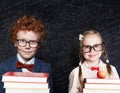 Back to school concept. Smart kids portrait. Little girl and boy student holding book and apple fruit against blackboard Royalty Free Stock Photo