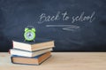 Back to school concept. stack of books and alarm clock over wooden desk in front of blackboard. Royalty Free Stock Photo