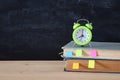 Back to school concept. stack of books and alarm clock over wooden desk in front of blackboard. Royalty Free Stock Photo