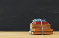 Back to school concept. stack of books over wooden desk in front of blackboard. Royalty Free Stock Photo