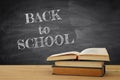 back to school concept. stack of books over wooden desk in front of blackboard. Royalty Free Stock Photo