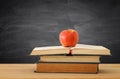 back to school concept. stack of books over wooden desk in front of blackboard. Royalty Free Stock Photo