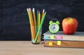 Back to school concept. stack of books and pencils over wooden desk in front of blackboard. Royalty Free Stock Photo