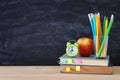 Back to school concept. stack of books and pencils over wooden desk in front of blackboard. Royalty Free Stock Photo