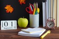 Back to school concept. School stationery. Notebook, books, alarm clock, green apple, pens, pencils and calendar dated