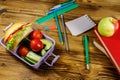 Back to school concept. School supplies, books, apple and lunch box with burgers and fresh vegetables on wooden table Royalty Free Stock Photo
