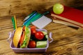 Back to school concept. School supplies, books, apple and lunch box with burgers and fresh vegetables on wooden table Royalty Free Stock Photo