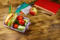 Back to school concept. School supplies, books, apple and lunch box with burgers and fresh vegetables on wooden table Royalty Free Stock Photo