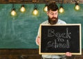 Back to school concept. Teacher in eyeglasses holding chalkboard with sentence back to school written in it. Man with Royalty Free Stock Photo