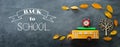 Back to school concept. Top view banner of school bus, alarm clock and pencil next to tree with autumn dry leaves over classroom Royalty Free Stock Photo