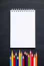 Back to school concept. Top view colored pencils and notebook top border on a chalkboard background. Flat lay and copy space Royalty Free Stock Photo