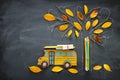 Back to school concept. Top view image of school bus and pencils next to tree sketch with autumn dry leaves over classroom blackbo Royalty Free Stock Photo