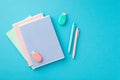 Back to school concept. Top view photo of colorful stationery stack of notepads pineapple shaped erasers and pens on isolated blue Royalty Free Stock Photo