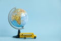 Back to school concept. Traditional yellow school bus and world globe on blue background. Transfer to school. Yellow toy Royalty Free Stock Photo