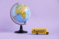 Back to school concept. Traditional yellow school bus and world globe on purple background. Transfer to school. Yellow Royalty Free Stock Photo