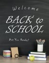 Back to school concept with writing on blackboard and desk, apple, books, stationery.